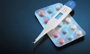 Cyfrowy termometr do ucha leży na blistrach z kolorowymi tabletkami. Czy termometr do ucha jest dokładny?