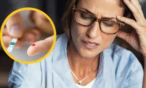 Kobieta z bólem głowy i kroplą krwi na palcu, symbolizującą hiperglikemię stresową.