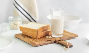 Kanapki z białego pieczywa i szklanka mleka na desce. Czy w mleku jest gluten? Pytanie o składniki śniadania.