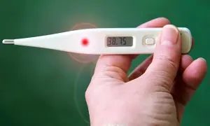Cyfrowy termometr pokazuje 38.75. Czuję, że temperatura na skroniach jest wyższa niż na czole, co sugeruje gorączkę.