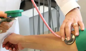 Lekarz mierzy ciśnienie krwi, słuchając stetoskopem. Obserwujemy fazy korotkowa podczas badania.