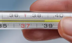 Termometr pokazuje 37,5°C. Skoki temperatury u dorosłego mogą mieć różne przyczyny, od infekcji po stres.