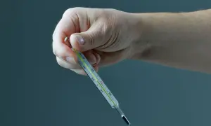 Dłoń trzyma termometr, na którym widać cienką, srebrzystą linię rtęci sięgającą do około 37,5°C.