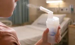 Dziecko wdycha lek przez komorę inhalacyjną dla dzieci w szpitalnym pokoju.