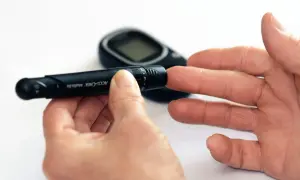 Ręka z nakłuwaczem i glukometrem. Ten dobry glukometr pomaga w codziennym monitorowaniu poziomu cukru.