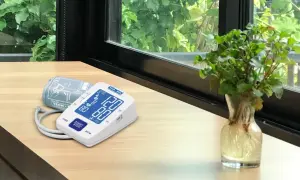 Cyfrowe symbole na ciśnieniomierzu TECH-MED pokazują odczyt 120/80. Obok leży mankiet.