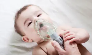 Niemowlę przechodzi nebulizację, czyli formę inhalacji, z maską na twarzy.