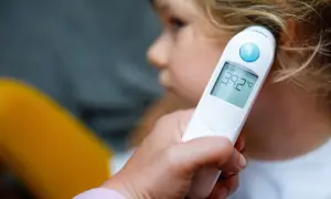 Dziecko ma gorączkę, termometr pokazuje 39.2°C.