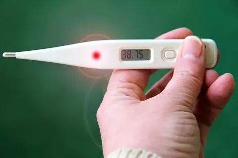 Cyfrowy termometr pokazuje 38.75. Czuję, że temperatura na skroniach jest wyższa niż na czole, co sugeruje gorączkę.