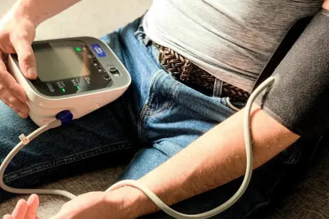 Mężczyzna mierzy ciśnienie Omronem. Na ekranie widoczny jest błąd E5, wskazujący na problem z mankietem.