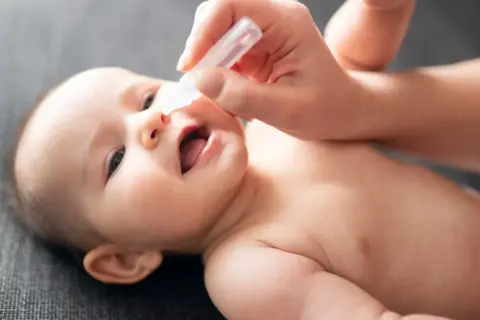 Pomoc mamie w walce z zatkanym nosem u niemowlaka w nocy. Krople do nosa przynoszą ulgę maluszkowi.
