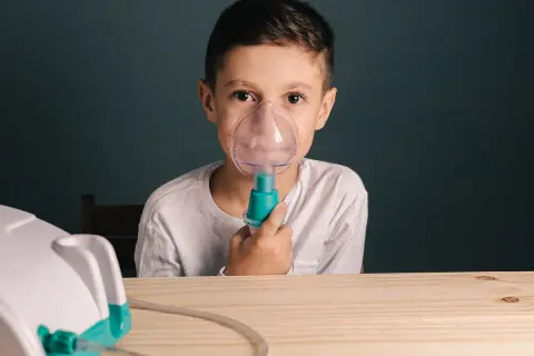 Chłopiec z maseczką inhalatora na twarzy. Czy po inhalacji można wychodzić na dwór?