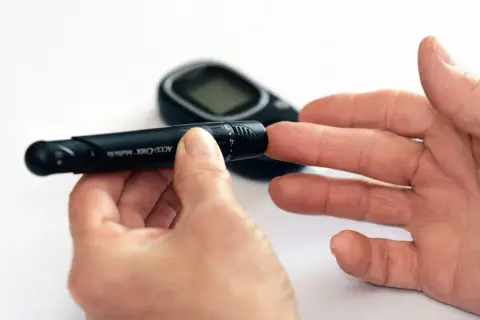 Ręka z nakłuwaczem i glukometrem. Ten dobry glukometr pomaga w codziennym monitorowaniu poziomu cukru.