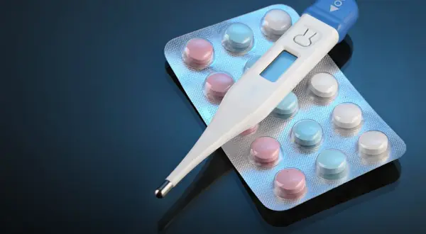 Cyfrowy termometr do ucha leży na blistrach z kolorowymi tabletkami. Czy termometr do ucha jest dokładny?