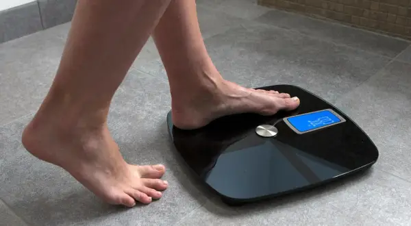 Kobieta stawia stopę na wadze elektronicznej, by sprawdzić, jak się ważyć. Wynik 62.5 kg.