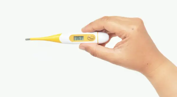 Dłoń trzyma termometr cyfrowy pokazujący 36.3°C. Pamiętaj, z jakiej odległości mierzyć temperaturę dla dokładnego wyniku.