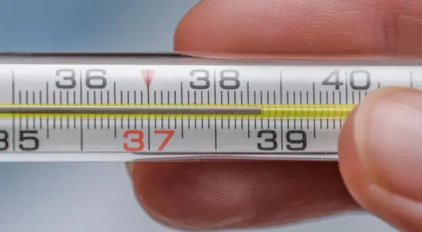 Termometr pokazuje 37,5°C. Skoki temperatury u dorosłego mogą mieć różne przyczyny, od infekcji po stres.