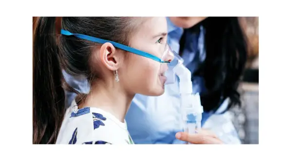 Dziewczynka z maską inhalatora Microlife. W dolnej części widać pojemnik, do którego wlewa się lek.