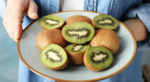 Talerz z pokrojonymi i całymi kiwi. Czy kiwi podnosi cukier? To pytanie nurtuje wiele osób dbających o zdrowie.
