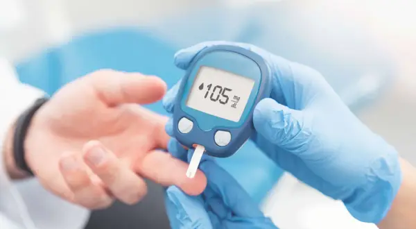 Rękawiczki medyczne i glukometr pokazują wynik 105 mg/dL. Dowiedz się, jak używać glukometru, by monitorować poziom cukru.