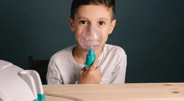 Chłopiec z maseczką inhalatora na twarzy. Czy po inhalacji można wychodzić na dwór?