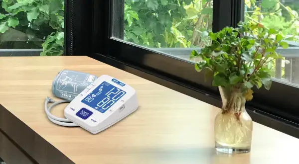 Cyfrowe symbole na ciśnieniomierzu TECH-MED pokazują odczyt 120/80. Obok leży mankiet.