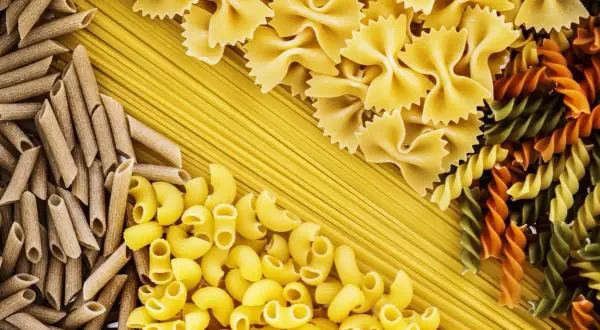 Różnorodne makarony: penne, kokardki, fusilli i spaghetti tworzą barwną tabelę węglowodanów.