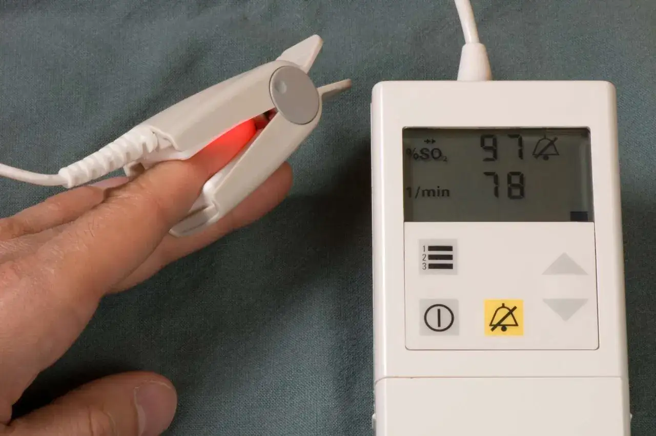 Pulsoksymetr na palcu pokazuje saturację 97% i tętno 78. To urządzenie monitoruje saturację 80 podczas snu, gdyby wystąpiły problemy.
