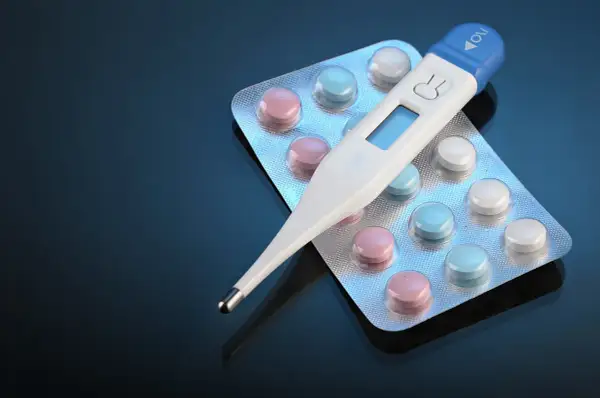 Cyfrowy termometr do ucha leży na blistrach z kolorowymi tabletkami. Czy termometr do ucha jest dokładny?