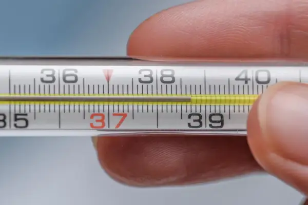 Termometr pokazuje 37,5°C. Skoki temperatury u dorosłego mogą mieć różne przyczyny, od infekcji po stres.