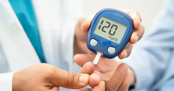 Glukometr na rękę pokazuje wynik 120 mg/dL. Osoba wykonuje pomiar cukru we krwi.