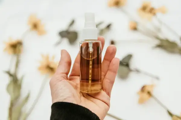 Dłoń trzyma buteleczkę z olejkiem eterycznym. Dowiedz się, jak używać olejków eterycznych do relaksu i pielęgnacji.