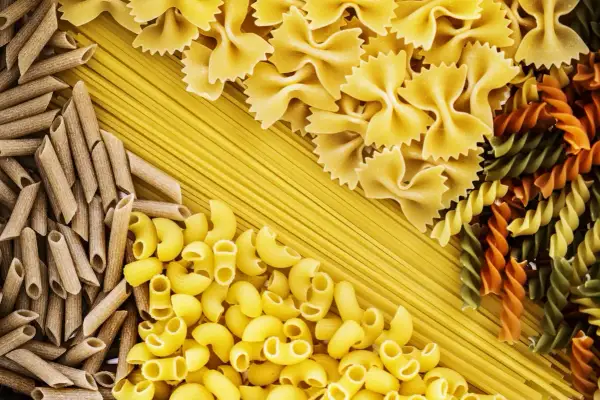 Różnorodne makarony: penne, kokardki, fusilli i spaghetti tworzą barwną tabelę węglowodanów.